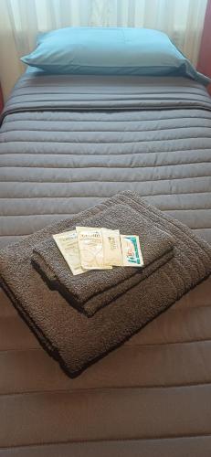 un letto con una coperta e un libro sopra di Casa céntrica compartida a Ushuaia