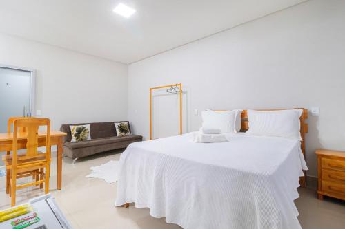 a bedroom with a large white bed and a couch at Pousada Meia Lua in Pirenópolis