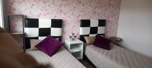 a bedroom with two beds and purple pillows at Galia Mohammedia residence POOL WIFI in Mohammedia