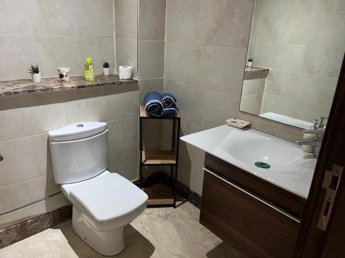 a bathroom with a white toilet and a sink at Galia Mohammedia residence POOL WIFI in Mohammedia