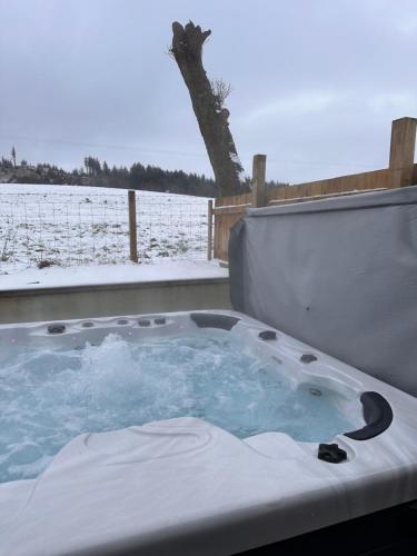 a jacuzzi tub with snow in a field at Woodlane lodge with private Hottub & Pool table in Dumfries