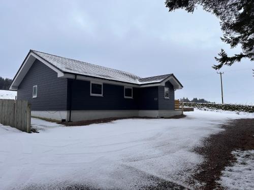 a blue house with snow in front of a driveway at Woodlane lodge with private Hottub & Pool table in Dumfries
