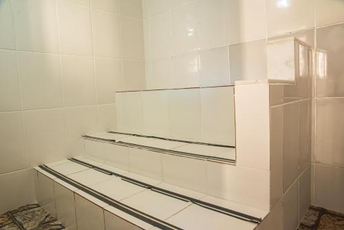a bathroom with white tiled walls and shelves at Pousada Locomotiva 206 in Conservatória