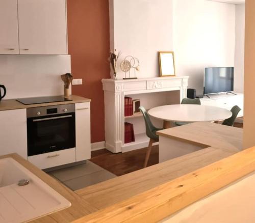 a living room with a table and a kitchen at Joli appartement en centre-ville in Chalon-sur-Saône