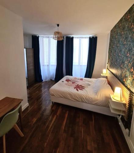 une chambre avec un lit et un bureau et deux fenêtres dans l'établissement Joli appartement en centre-ville, à Chalon-sur-Saône