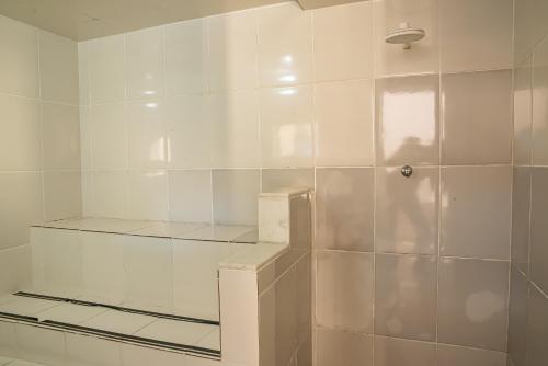 a bathroom with a shower with white tiled walls at Pousada Locomotiva 206 in Conservatória