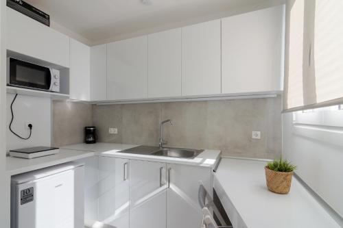 a white kitchen with a sink and a microwave at Parliament Sq Studio Apt in Athens
