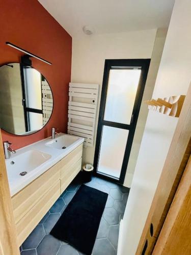 une salle de bain avec un lavabo et un miroir dans l'établissement Très belle maison au calme entre centre et plages, à Capbreton