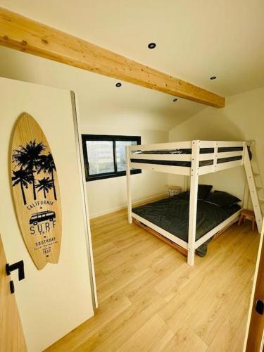 Cette chambre comprend 2 lits superposés et une planche de surf murale. dans l'établissement Très belle maison au calme entre centre et plages, à Capbreton