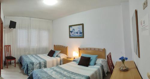 Habitación de hotel con 2 camas, mesa y escritorio en Hostal La Llave, en Mave
