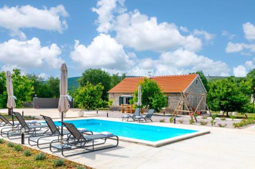 a swimming pool with chairs and a house at Villa Lea&Robi in Unešić