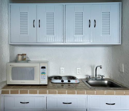 a kitchen counter with a microwave and a sink at Beach and Ocean Front Apartments Cancun in Cancún