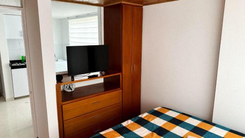 a bedroom with a television in a wooden cabinet at aparta estudio INTELIGENTE Tunja al lado de la UPTC in Tunja