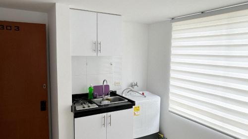 a kitchen with white cabinets and a sink and a window at aparta estudio INTELIGENTE Tunja al lado de la UPTC in Tunja