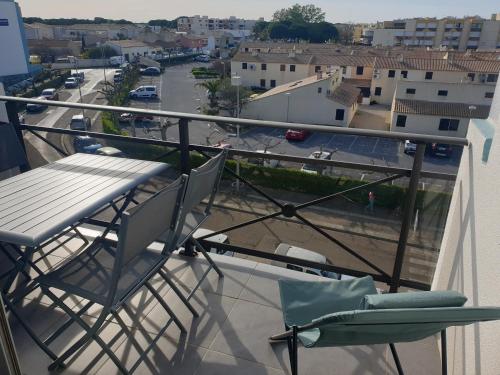 d'un balcon avec une table, des chaises et une rue. dans l'établissement Double studio cabine Grau du Roi, au Grau-du-Roi
