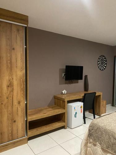 a bedroom with a bed and a desk and a television at Serra Negra Pousada Spa in Guarapari