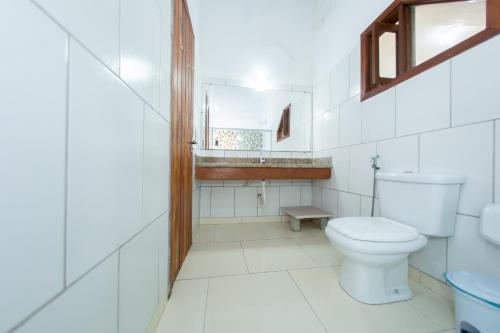 La salle de bains blanche est pourvue de toilettes et d'un lavabo. dans l'établissement Pousada Flor do Arraial, à Arraial d'Ajuda