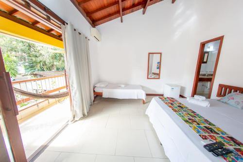 a bedroom with two beds and a balcony at Pousada Flor do Arraial in Arraial d'Ajuda