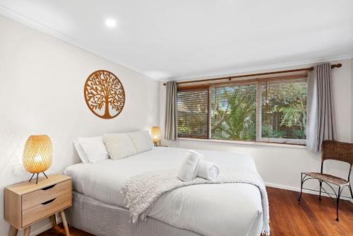 a white bedroom with a bed and a window at Park Cottage Barwon Heads in Barwon Heads