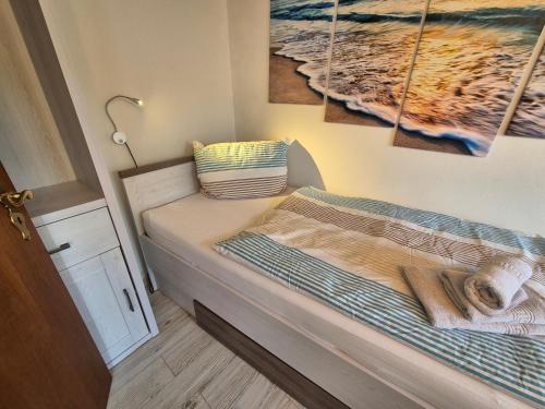 a small bed in a room with paintings on the wall at Ferienhaus Herzmuschel in Norddeich