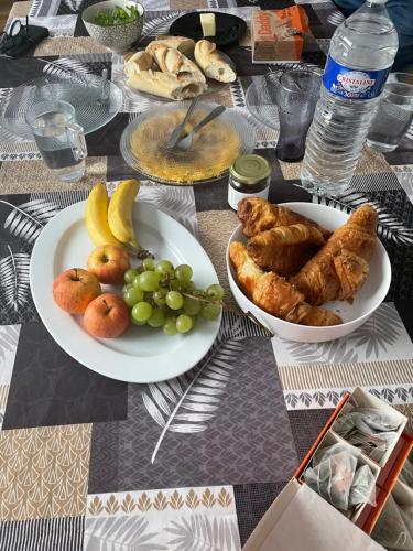 a table with two plates of food and fruit at Chambre avec vue sur la campagne! in Saint-Clair-sur-Epte