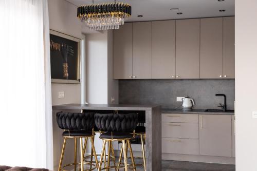 a kitchen with white cabinets and black bar stools at VIXI Skylum in Vilnius
