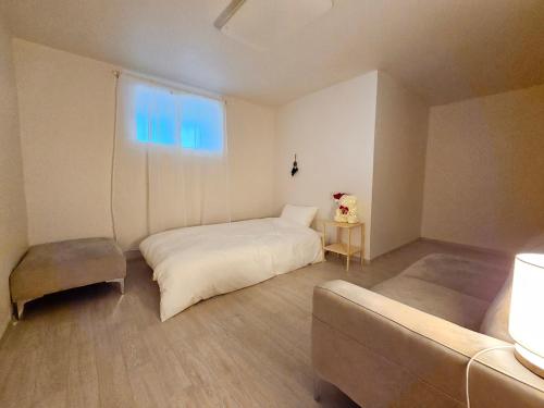 a bedroom with a bed and a couch and a window at H Stay in Incheon