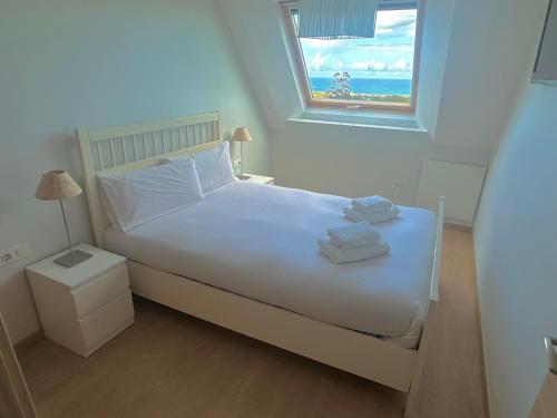 een slaapkamer met een wit bed en handdoeken bij Arnela Reinante in Barreiros