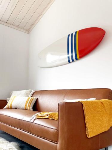 a surfboard hanging on a wall above a couch at Fish Board Studio includes King Bed with Kitchenette and Futon in Stinson Beach