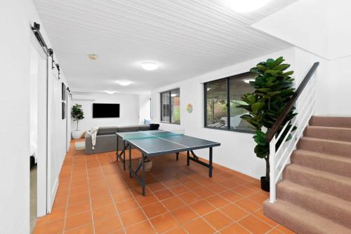a living room with a ping pong table and stairs at Seafarers Horizon oceanfront retreat in Ocean Grove