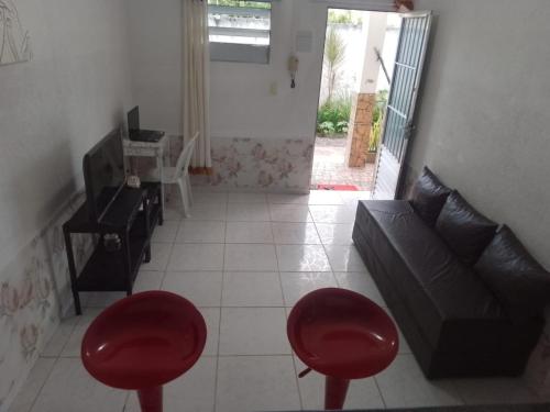 ein Wohnzimmer mit einem Sofa und zwei roten Stühlen in der Unterkunft AP03-A 50 Metros da Praia Flats Mobiliados para 4 pessoas in Paulista