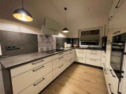a kitchen with white cabinets and stainless steel appliances at Modernes Haus mit Wintergarten in Immenhausen