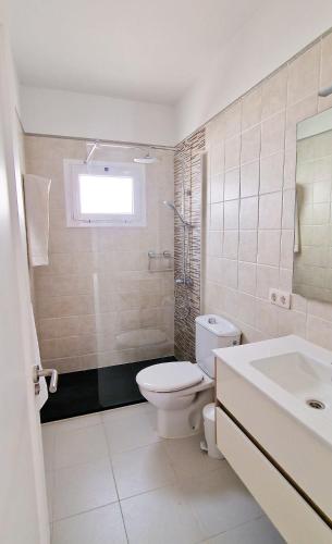 a white bathroom with a toilet and a sink at Apartamento de la Playa II in Tías