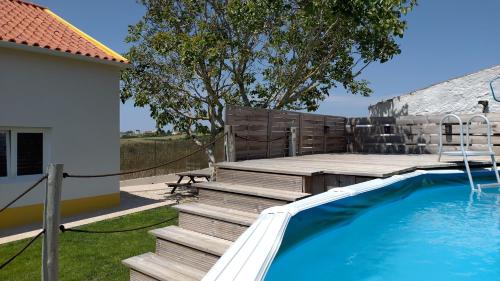 a backyard with a pool and wooden steps and a house at Casa da Caroleira in Paços