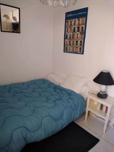 - une chambre avec un lit bleu et une table avec une lampe dans l'établissement Appartement vue sur canal proximité mer, à Sète