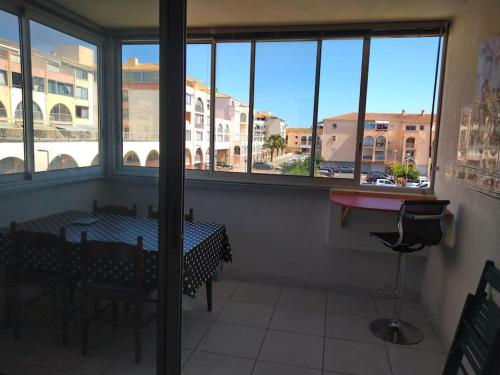 une pièce avec une table, des chaises et des fenêtres dans l'établissement Appartement vue sur canal proximité mer, à Sète