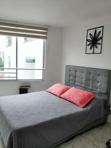 una camera da letto con un grande letto con un cuscino rosso di Apartamento con la mejor ubicación y descanso ad Armenia