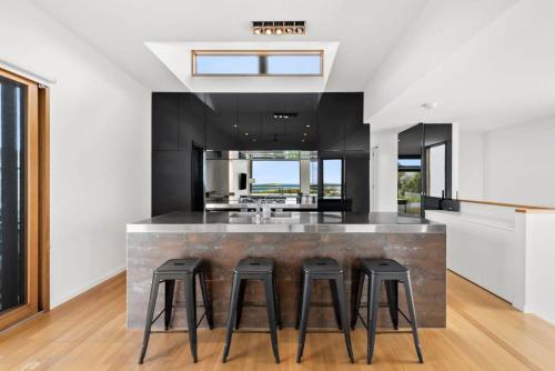 a kitchen with a bar with four stools at Mariners Retreat Unrivalled Ocean and River Views in Ocean Grove