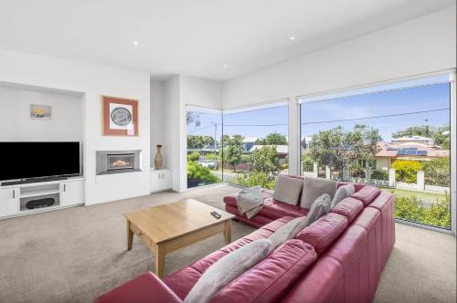 a living room with a purple couch and a tv at Saltwater Serenity - Townhouse with a View in Torquay