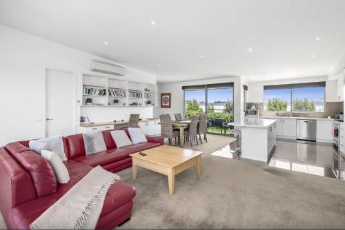 a living room with a red couch and a table at Saltwater Serenity - Townhouse with a View in Torquay
