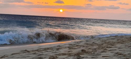 a beach with the sun setting over the ocean at Casa Blu Guesthouse - Casa de Hospedes in Santa Maria