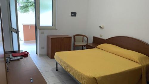 1 dormitorio con cama amarilla y escritorio en Villaggio La Giara, en Vieste