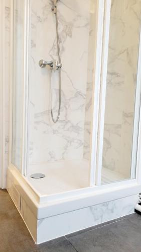La salle de bains est pourvue d'une douche et d'un mur en marbre blanc. dans l'établissement Clichy Luxe Living, à Clichy