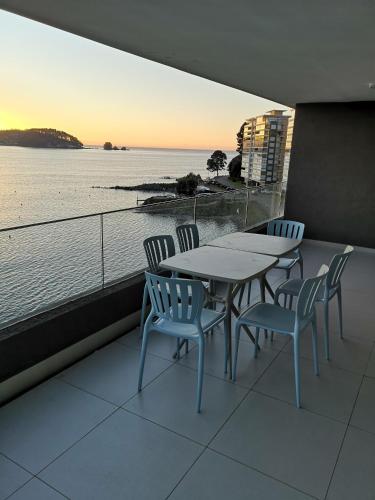 a table and chairs with a view of the water at Departamento de Lujo Pingueral in Concepción