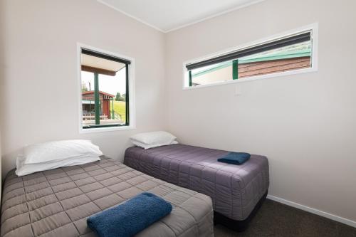 two beds in a room with two windows at Blue Lake TOP 10 Holiday Park in Rotorua