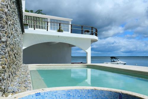 uma piscina em frente a um edifício com o oceano em Casa Bacalar em Bacalar