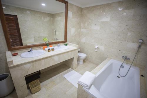 uma casa de banho com 2 lavatórios, uma banheira e um espelho. em Hotel Buenavista Dakhla em Dakhla