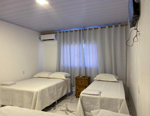 two beds in a hospital room with a window at Hotel WM in Teresina de Goias