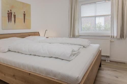 - une chambre avec un lit doté de draps blancs et une fenêtre dans l'établissement 50034..., à Carolinensiel
