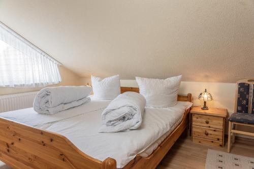 una camera da letto con letto in legno, lenzuola e cuscini bianchi di 50178... a Harlesiel